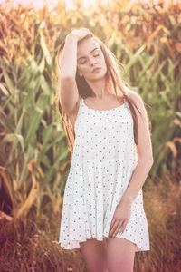 Young woman standing against hay