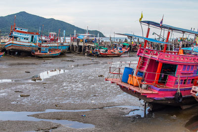 Fishing boats moored on beach against sky