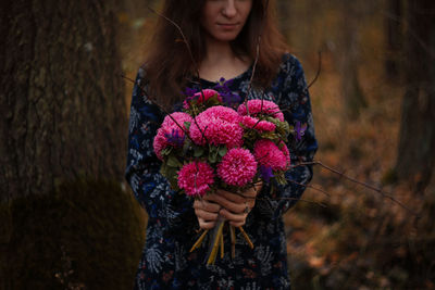 Low section of woman standing on purple flowering plants
