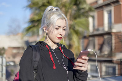 Young woman using smart phone while standing in city