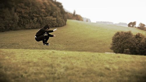 Side view of man jumping on grassy field