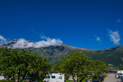 Scenic view of trees and mountains against blue sky