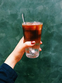 Midsection of person holding drink on glass