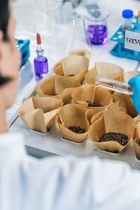 Scientist pouring chemical in dirt at laboratory