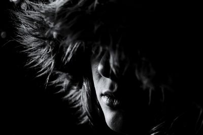 Close-up of young woman wearing fur in dark