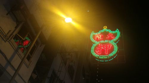 Low angle view of illuminated lighting equipment hanging at night