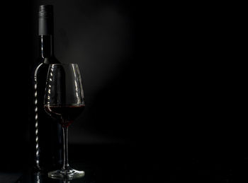 Glass of wine bottles against black background