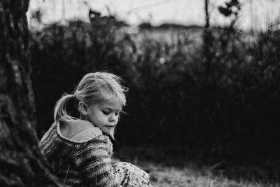 Cute girl sitting by tree