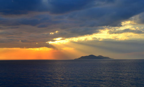 Scenic view of sea against cloudy sky at sunset