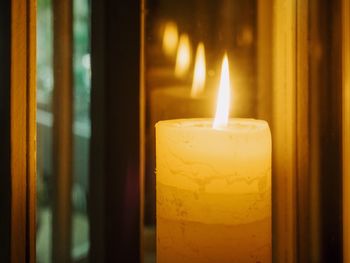Close-up of illuminated candles on glass