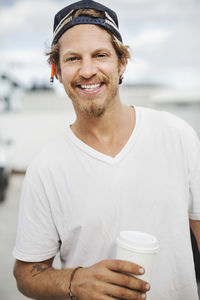 Portrait of happy carpenter holding disposable cup outdoors