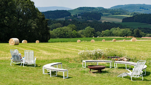 Chairs on agricultural field against sky
