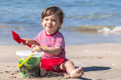 Little boy playing with bucket and spade on the seashore on the beach