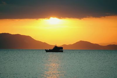 Silhouette ship on sea against sky during sunset