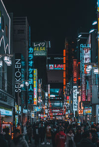 People on illuminated street in city at night