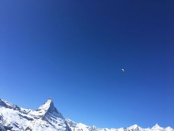 Low angle view of paraglider against blue sky