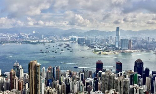 Aerial view of city by sea against sky