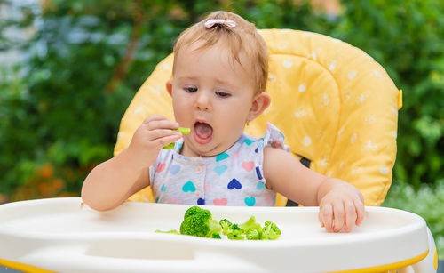 Cute baby eating broccoli