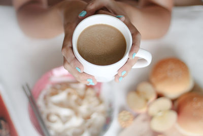 High angle view of hands holding coffee cup on breakfast table