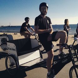 Young man sitting on bicycle at beach