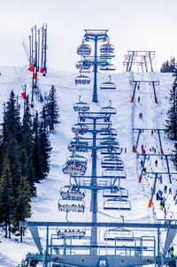 Ski lift over snow covered mountains against sky