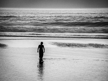 Rear view of silhouette man walking in sea