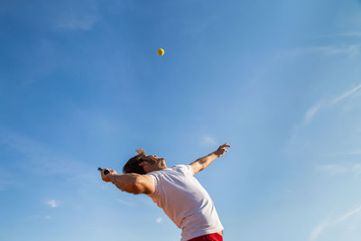 Low angle view of man playing tennis against sky