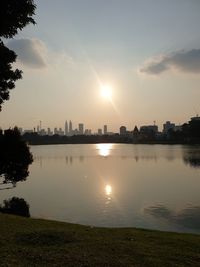 Scenic view of lake by buildings against sky during sunset