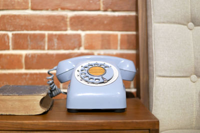 Vintage telephone on table against brick wall