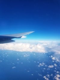 Aerial view of airplane wing over sea against blue sky