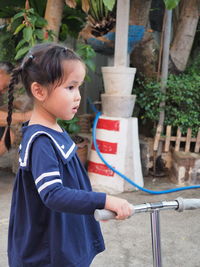 Side view of girl looking away while standing by push scooter