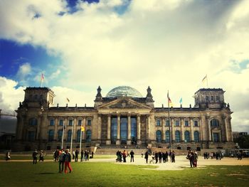 People in front of the reichstag against cloudy sky