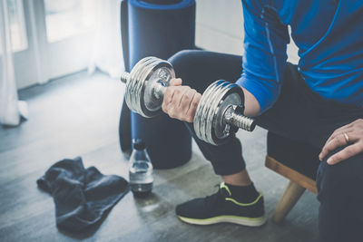 Sporty man working out and trains at home. fit male doing exercise with dumbbells weights for biceps