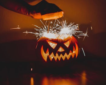 Close-up of illuminated hand holding pumpkin