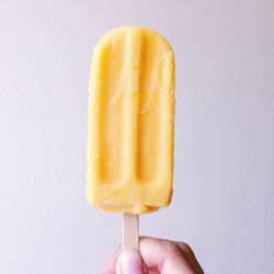 Hand holding ice cream cone against white background