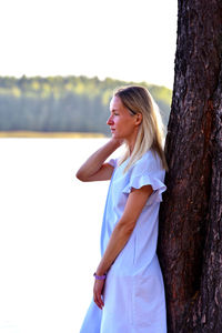 Side view of woman standing on tree trunk