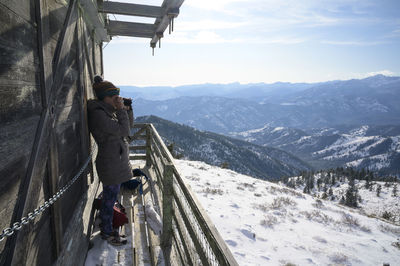 Female taking photograph from a fire lookout in the mountains