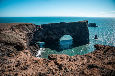 Rock formations on shore against blue sky