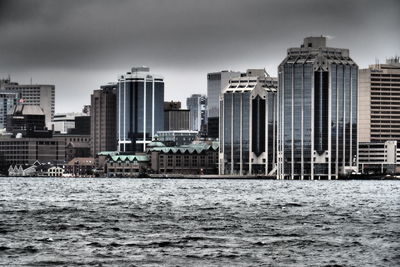 Sea by buildings against sky in city