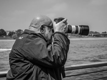 Rear view of man photographing sea against sky