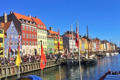 Boats in canal by buildings against sky in city