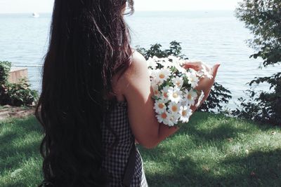 Midsection of woman standing by sea