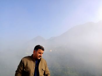 Young man standing on mountain against sky