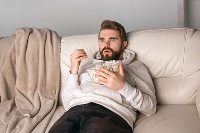 Full length of man sitting on sofa at home