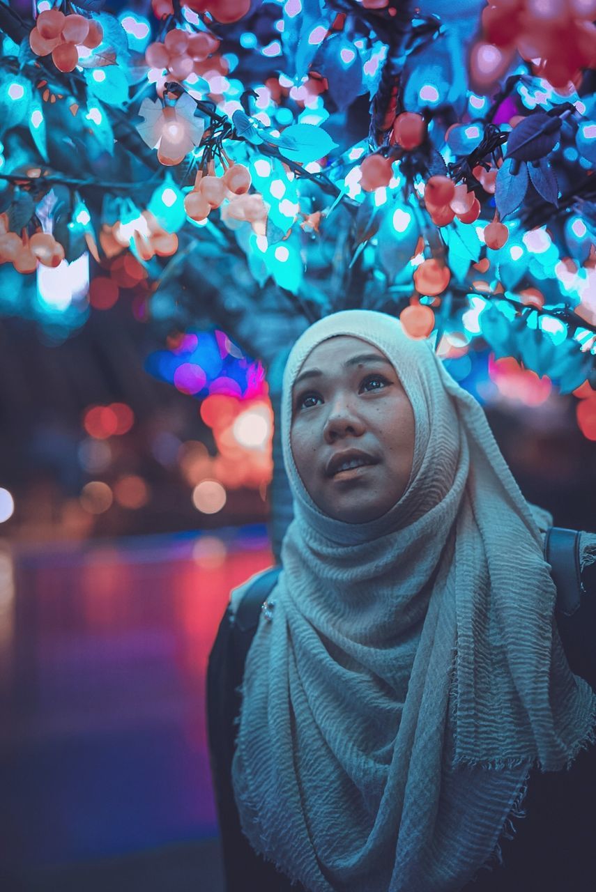 one person, portrait, real people, front view, focus on foreground, hijab, leisure activity, headscarf, looking at camera, clothing, illuminated, young adult, lifestyles, headshot, looking, young women, waist up, standing, night, warm clothing, hood - clothing