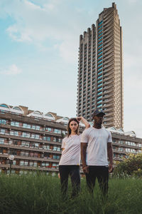 Man and woman against modern buildings against sky