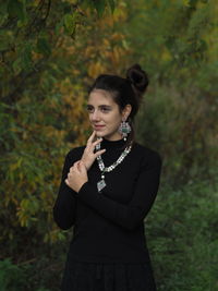 Young woman standing against trees