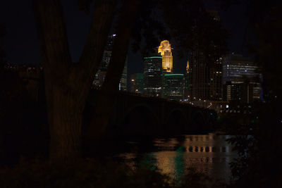 Illuminated bridge over river in city at night