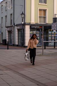 Full length of man walking on footpath in city