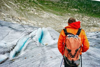 Rear view of hiker with backpack standing on mountain